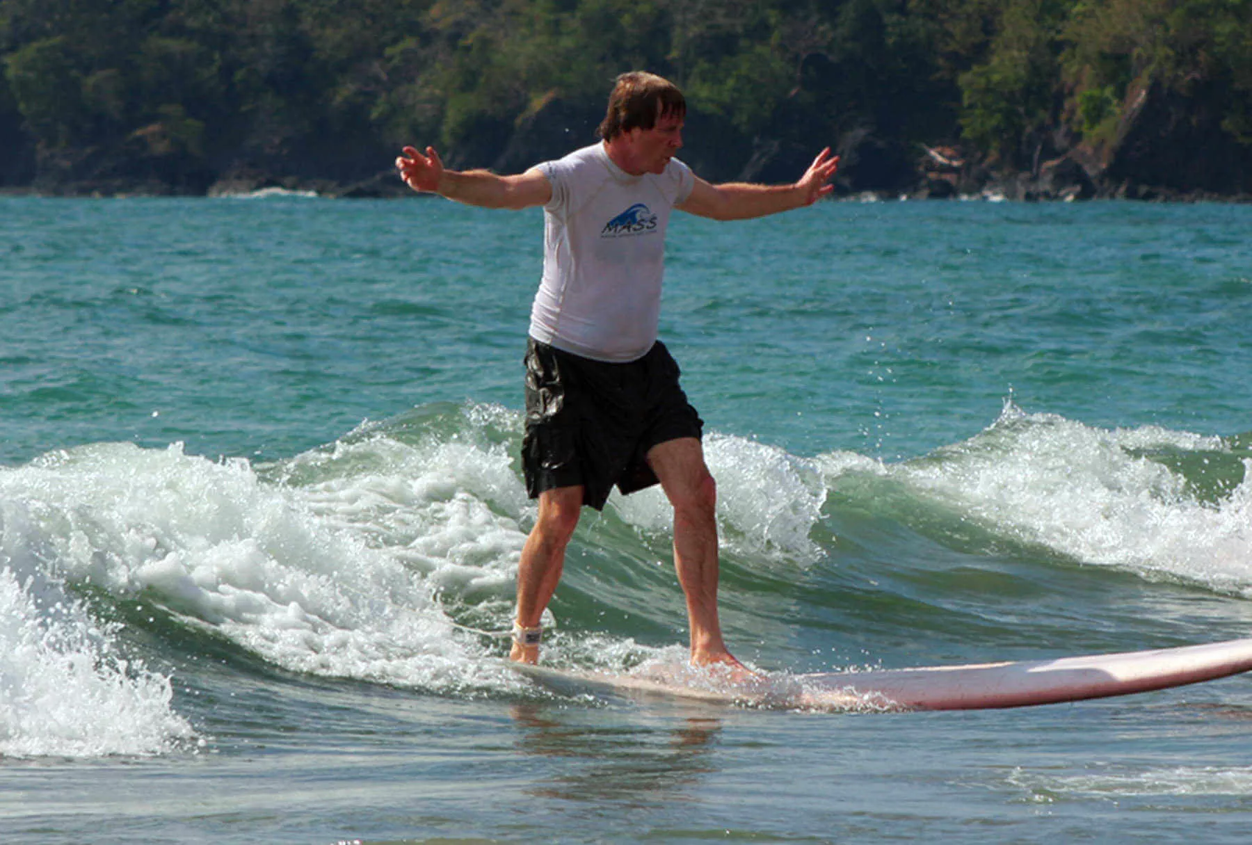 It takes a while, but Rick Steves finally learns how to stand up on a surfboard